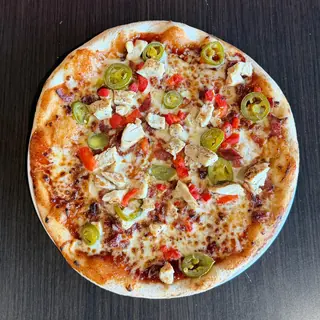 The BBQ Clucker, a Longshot specialty pizza seen from above: house BBQ Sauce, Mozzarella & Provolone, Grilled Chicken, Bacon, Roasted Red Pepper, Jalapeños, on a blistered brick-oven crust