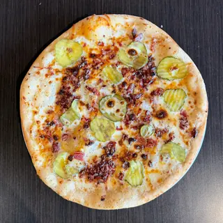 The Dill Pickler, a Longshot specialty pizza seen from above: white Garlic Sauce, Mozzarella & Provolone, Dill Pickles, Bacon, Cheddar, Ranch Drizzle, on a blistered brick-oven crust