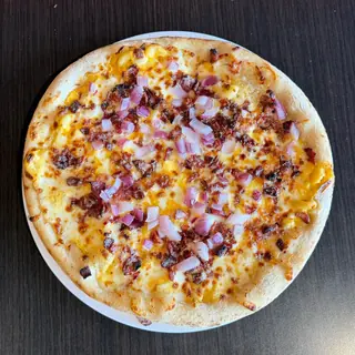 The Midwest Mac, a Longshot specialty pizza seen from above: mac & Cheese, Mozzarella & Provolone, Bacon, Cheddar, Red Onion, on a blistered brick-oven crust