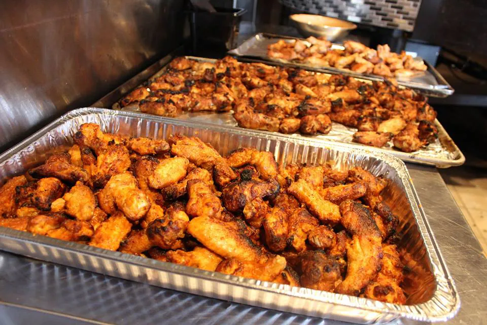 Two full foil trays of oven-baked Longshot wings ready for a large order