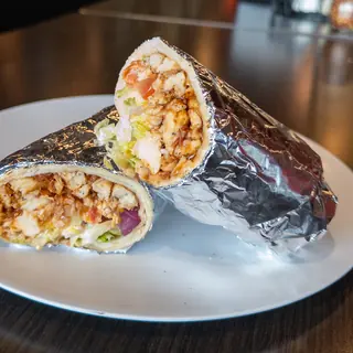 BBQ Chicken Wrap, halved on a white plate so the filling shows: grilled Chicken, Cheddar, Romaine Lettuce, Tomato, Red Onion, House BBQ Sauce. Served warm in foil.